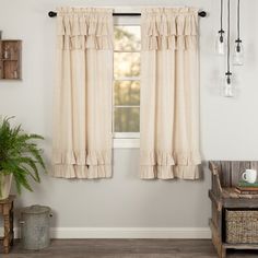 a living room with a window covered in ruffled curtains and a potted plant