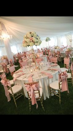 tables and chairs are set up for a wedding reception with pink sashes on them