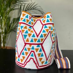 a white and red bag sitting on top of a table next to a potted plant