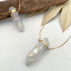 Long thought of as a symbol of good luck and protection our Angel Aura Amulet Necklace is infused with good vibes. This modern-day talisman looks stunning worn alone or in layered looks. A gorgeous addition to your handmade jewelry collection and must-have for gemstone lovers. Angel Aura Quartz is known for its healing properties. It is said to stimulate the immune system, balance the body’s mind and soul, and strengthen your energy level. To foster a stronger sense of connection with others, op Gold Amulet Dangle Necklace, Handmade Gold Amulet Crystal Necklace, Crystal Amulet Necklaces For Healing, Silver Healing Amulet Necklace, Shell Charm Necklace, Angel Aura Quartz Necklaces, Spiritual Necklace, 20 Inch Necklace, Good Luck Necklace