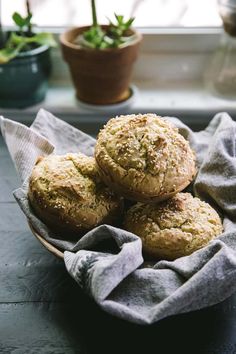 some muffins are sitting in a bowl on a table next to a potted plant