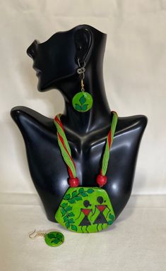 a black mannequin with green and red necklaces on it's head