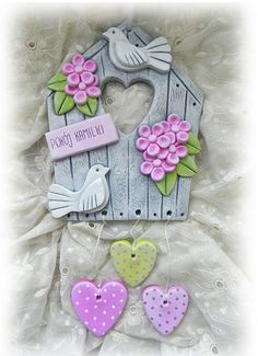 a birdhouse with flowers and two hearts hanging from it's side, on a white background