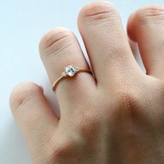 a woman's hand with a diamond ring on top of her left hand, against a white background