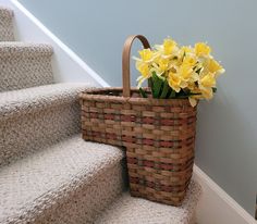 a basket with yellow flowers sitting on top of the stairs next to some carpeted steps