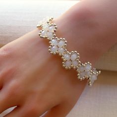 About this item-- Elevate your style with this delicate four-leaf clover bracelet, crafted with exquisite milky white crystals and silver seed beads. It features a matching silver-colored toggle clasp for a secure and stylish closure, all woven together with super-strong, micro-fused braided thread. Perfect for any occasion, this bracelet is a must-have addition to your jewelry collection! One-of-a-kind piece available in only one size. Please take a moment to check the measurements to ensure a perfect fit. Specs-- Measurement: length - 190 mm (7.5 inches) width - 17 mm (0.66 inches) Material: crystal, Japanese galvanized silver (plated) bead, micro-fused braided thread Color: white, silver Hardware: toggle clasp Weight: 20 grams Production ID: BR051 Handmade White Crystal Bracelet With Flower Shape, Handmade Dainty Pearl White Bracelets, Handmade White Crystal Bracelet In Flower Shape, Handmade White Crystal Flower Bracelet, Delicate White Flower Beaded Bracelets, Delicate White Flower Shaped Beaded Bracelets, Handmade Delicate Pearl Beaded Bracelets, Delicate White Crystal Bracelet Gift, Elegant Beaded Flower-shaped Jewelry