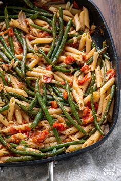 a skillet filled with pasta and green beans