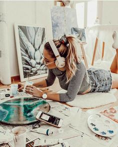 a woman is laying on the floor with her headphones over her eyes and painting