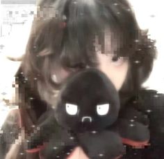 a woman holding a black stuffed animal in front of her face