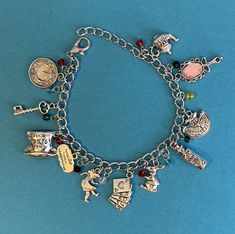 Charms adorn this silver toned bracelet all inspired by the Alice in Wonderland story. Makes for a memorable gift to anyone who loves the story. Alice In Wonderland Charm Bracelet, Whimsical Silver Charms For Gifts, Whimsical Silver Dangling Charms, Themed Multicolor Jewelry With Charms, Multicolor Themed Jewelry With Charms, Whimsical Nickel-free Charm Bracelet Gift, Whimsical Nickel Free Charm Bracelet Gift, Nickel-free Themed Charm Bracelet As Gift, Multicolor Themed Charm Bracelet As Gift