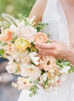 a woman holding a bouquet of flowers in her hands and wearing a wedding ring on her finger