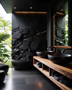 a black bathroom with two sinks and a large mirror on the wall next to it