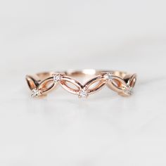 a rose gold ring with three diamonds on the top and bottom, sitting on a white surface