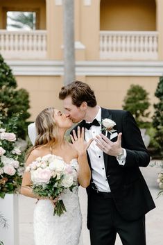 a bride and groom kissing in front of an arch with flowers on it at their wedding