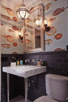 a bathroom with a sink, toilet and wallpapered walls in the background that has fish on it