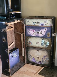 an old suitcase with butterflies painted on the side and drawers opened to reveal its contents