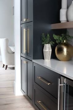 a kitchen with black cabinets and gold vases