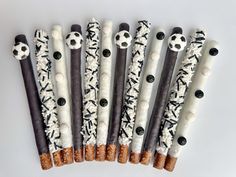 six soccer themed pretzels are lined up in a row with black and white sprinkles