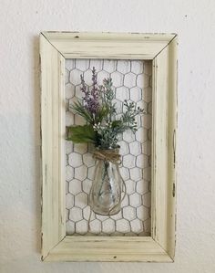 a vase with flowers in it hanging on a wall