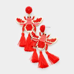 two red tasselled earrings with fringes and beads on top of each other