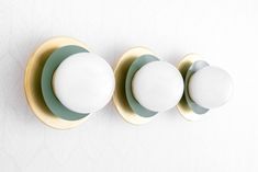 three white and green plates mounted on a wall next to each other, with gold rims