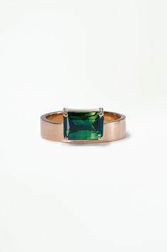 a gold ring with an emerald green tourmaline stone set in the center, on a white background