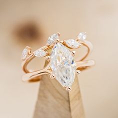 an engagement ring with a pear shaped diamond surrounded by smaller pear shaped diamonds on top