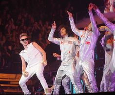 the group of young men are performing on stage with their hands up in the air