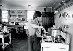 a shirtless man cooking in a kitchen with pots and pans on the stove