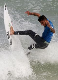 a man riding a surfboard on top of a wave in the ocean with his arms out