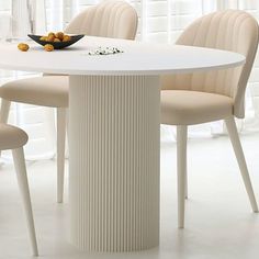 a white table with four chairs around it and a bowl of fruit on the table