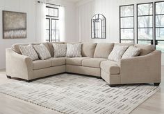 a living room with a large sectional couch and lots of pillows on the rugs