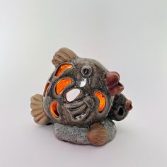 a ceramic fish with an orange light in its mouth