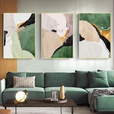 three paintings hang on the wall above a green couch in a living room with a coffee table