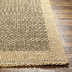 a brown rug on top of a wooden floor next to a white and black cat