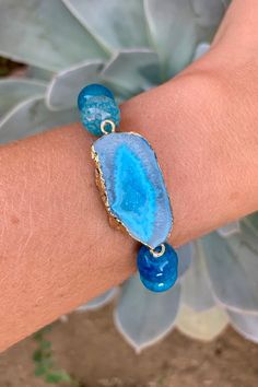 "Stunning bracelet with beautiful 10mm aqua blue Dragon's Vein Agate Beads and a matching gold plated Druzy Agate Geode Slice Pendant. The pendant is 0.5 inches long and 1.25 inches wide. The bracelet is elastic with a length of 7\" unstretched. Item will be shipped 1 - 2 business days after purchase. \"Dragon's Veins Agate can heighten creative visualization. It strengthens the ability and will to manifest one's life purpose on the earth planet. Promotes energy and strength, and will help one d Blue Agate Geodes With Natural Stones, Blue Agate Geodes, Blue Gemstone Stretch Bracelet As Gift, Adjustable Blue Gemstone Stretch Bracelet, Blue Beaded Agate Bracelets, Blue Agate Round Beads Crystal Bracelet, Handmade Blue Agate Bracelets, Blue Agate Beaded Bracelets For Gift, Hand-strung Blue Agate Bracelets