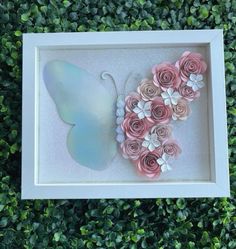 a white frame with pink flowers and a butterfly on the side in front of some green bushes