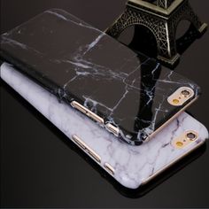 two iphone cases sitting next to each other on top of a black surface with the eiffel tower in the background