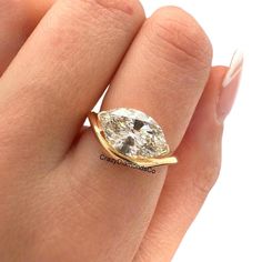 a woman's hand with a diamond ring on top of her finger, showing the center stone