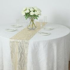 a white table topped with a vase filled with flowers and two empty glasses on top of it