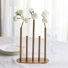 three wooden vases with flowers in them on a table next to plates and glasses