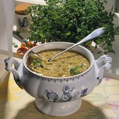 a white bowl filled with soup next to a potted plant on top of a table