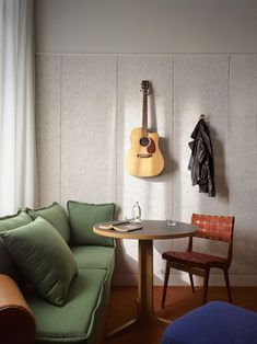 a room with a couch, table and guitar hanging on the wall next to it