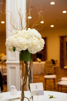 a tall vase filled with white flowers on top of a table