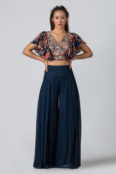 Navy blue crop top with floral print on the base, embroidery in a floral pattern and ruffle sleeves. Comes with flared pants.
Component: 2
Pattern: Print and Embroidery
Type Of Work: Floral Print, Sequin, Cutdana, Beads and Thread
Neckline: V neck
Sleeve Type: Ruffle Sleeves
Fabric: Crepe and Georgette Crepe
Color: Blue
Other Details: 
Ruffle sleeves
Pleated flared pants
Overlapping V neckline
Occasion: Destination Wedding - Aza Fashions Ethnic Crop Top, Plazo Dress, Plazo Pant, Top And Plazo, Indian Dress Up, Navy Blue Crop Top, Designer Lehengas, Lehenga Blouse Designs, Floral Print Crop Top