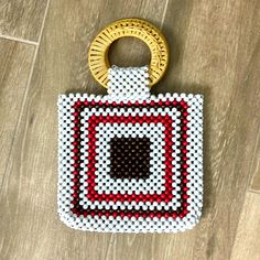 a beaded purse sitting on top of a wooden floor next to a golden ring