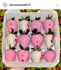 a box filled with lots of pink and white strawberries covered in candy hearts on top of each other