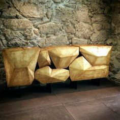 a wooden bench sitting in front of a stone wall