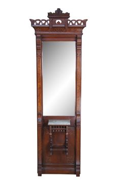 an antique wooden mirror with ornate carvings on the top and bottom, sitting against a white background