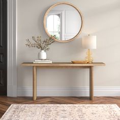 a wooden table with a mirror on top of it next to a lamp and door